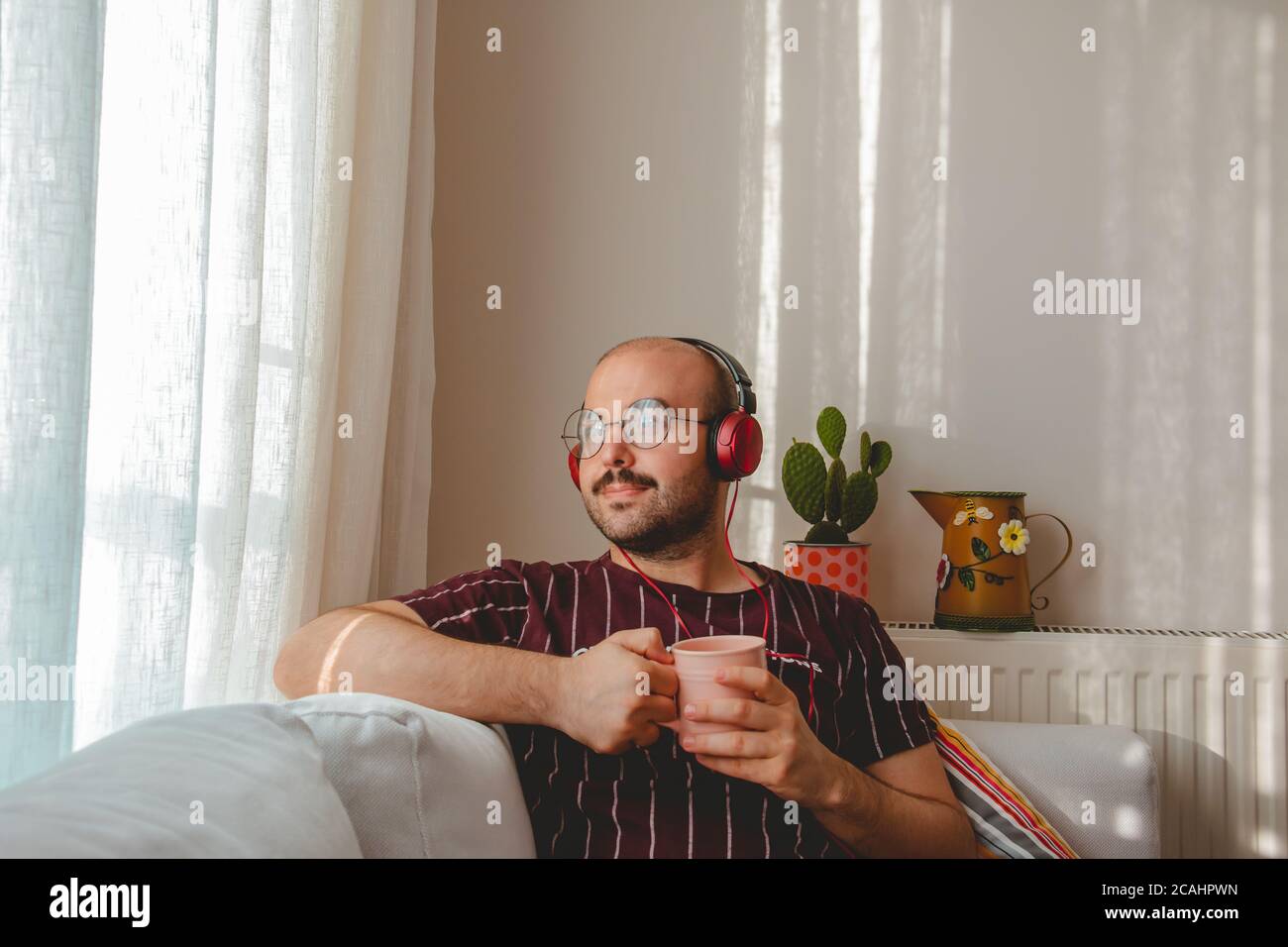 Junge Leute haben eine gute Zeit zu Hause. Musik hören, Kaffee und Tee trinken. Ruhender Teenager läuft mit Tablet und Leptop in den Händen. Stockfoto