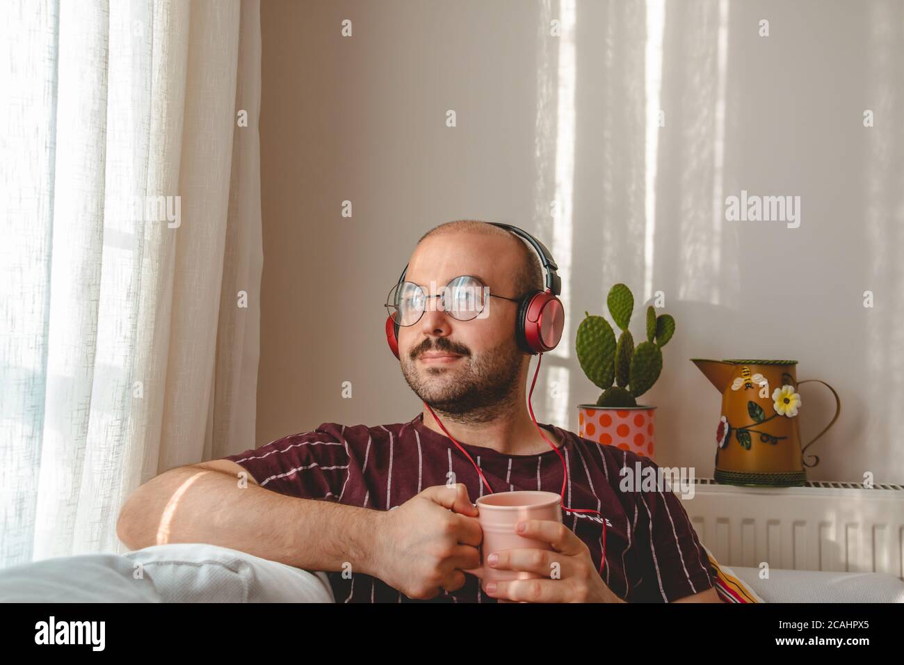Junge Leute haben eine gute Zeit zu Hause. Musik hören, Kaffee und Tee trinken. Ruhender Teenager läuft mit Tablet und Leptop in den Händen. Stockfoto