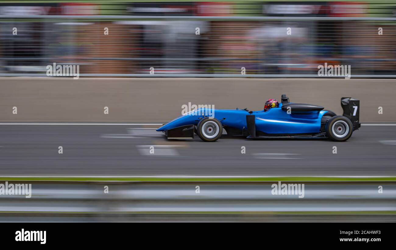 Eine Schwenkaufnahme eines blauen Rennwagens, der eine Strecke fährt. Stockfoto