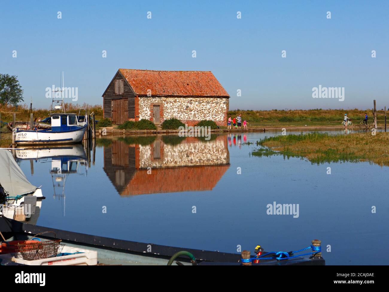 Ein Blick auf die alte Coal Barn und Hafen mit einer Familie Krabbenfischen im Sommer an der North Norfolk Küste in Thornham, Norfolk, England, Großbritannien. Stockfoto