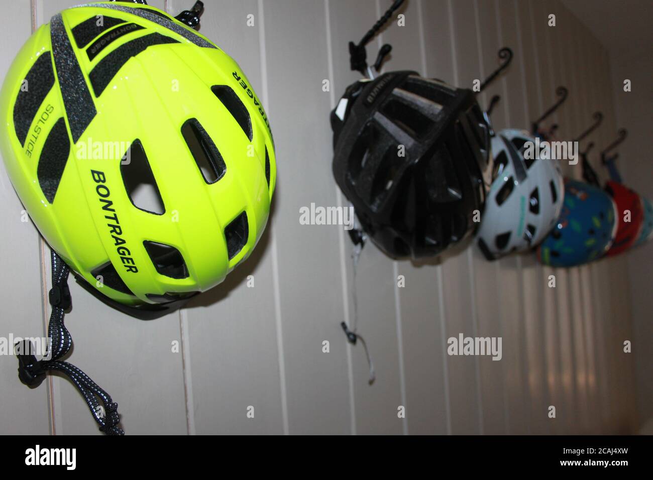 Eine Reihe von Fahrradhelmen, die an einer Wand hängen Stockfoto