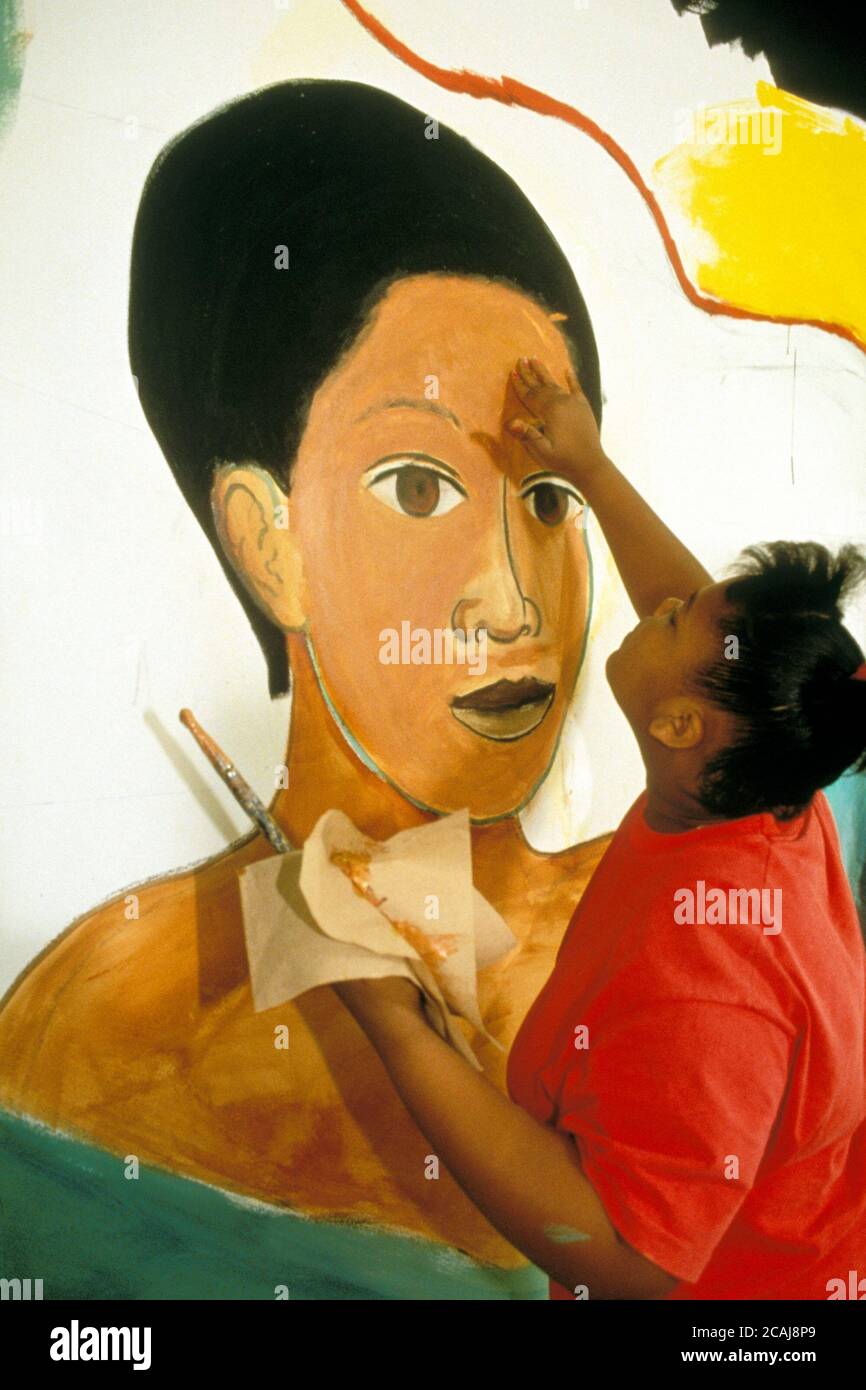 Schwarzes Teenager-Mädchen, das Wandgemälde an der Wand im Schulgebäude malte. Modellversion. ©Bob Daemmrich Stockfoto