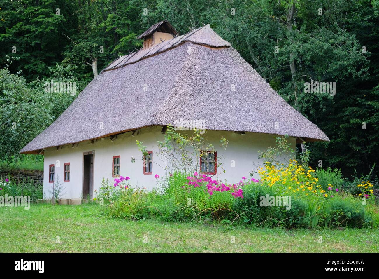 Altes Landhaus mit Strohdach und weiß getünchten Wänden. Historisches Dorf in der Ukraine, Erhaltung der Traditionen und Kultur. Stockfoto