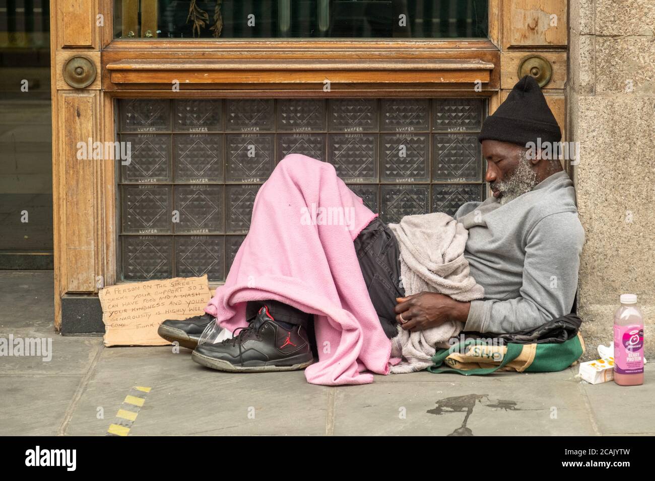 London - August 2020: Obdachloser sitzt in der Tür auf der Londoner Straße Stockfoto