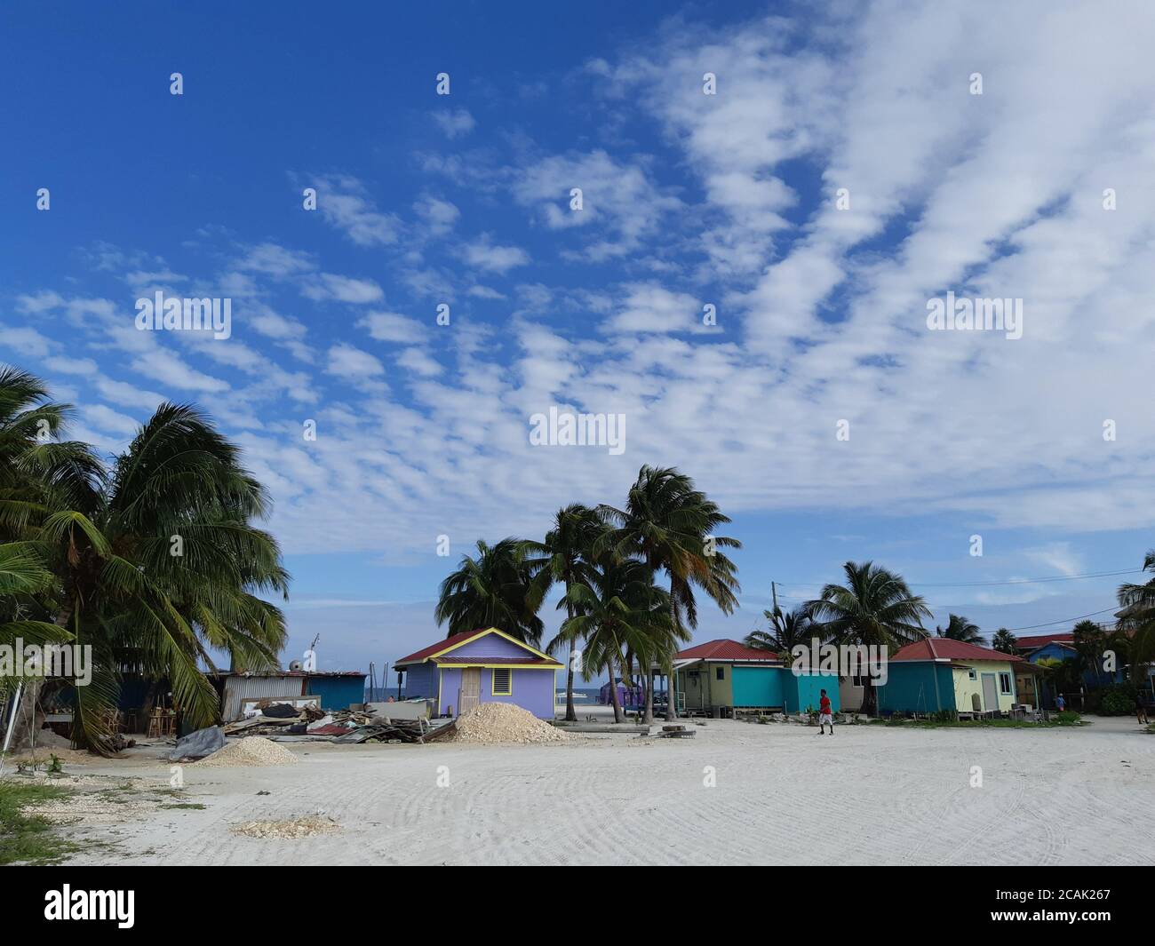 Bunte Häuser und Strand mit Palmen in Caye Caulker, Belize. Stockfoto