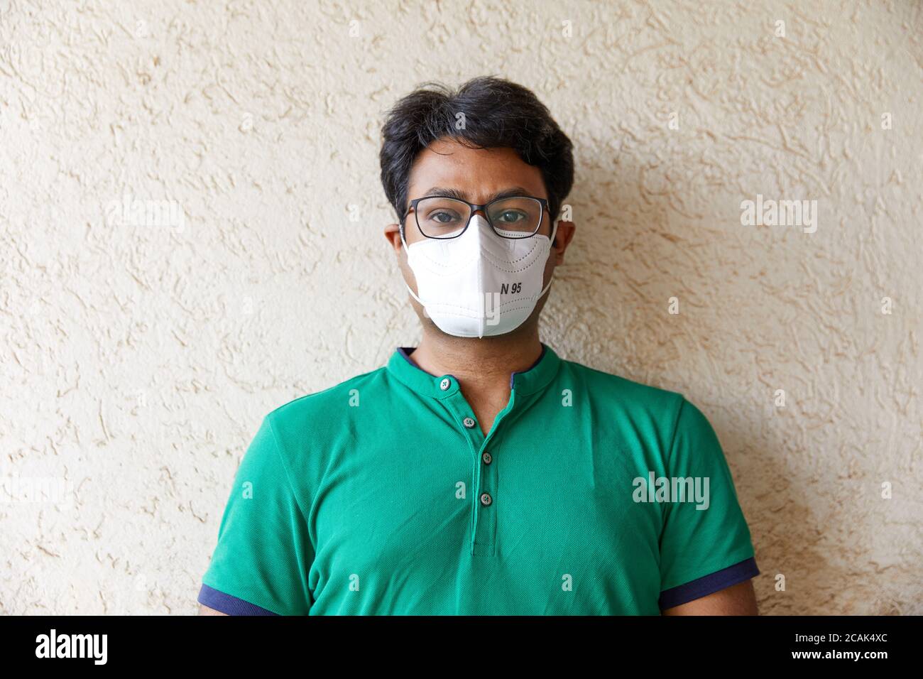 Mittlere Aufnahme von Erwachsenen Südasiatisch (indisch) Männlich trägt ein Grünes T-Shirt und eine weiße N95 Atemschutzmaske mit Body und Mit der Vorderseite und der Kamera Stockfoto