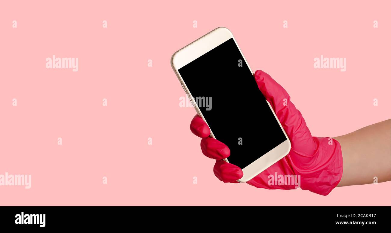 Hand in Handschuhe halten Smartphone mit mockup auf rosa Hintergrund. Kontaktloser Einkauf und Lieferung. Stockfoto