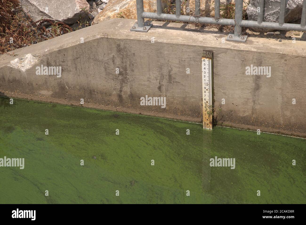 Ein Guage misst den Wasserstand an einem wasserbetriebenen Mühlendamm. Stockfoto