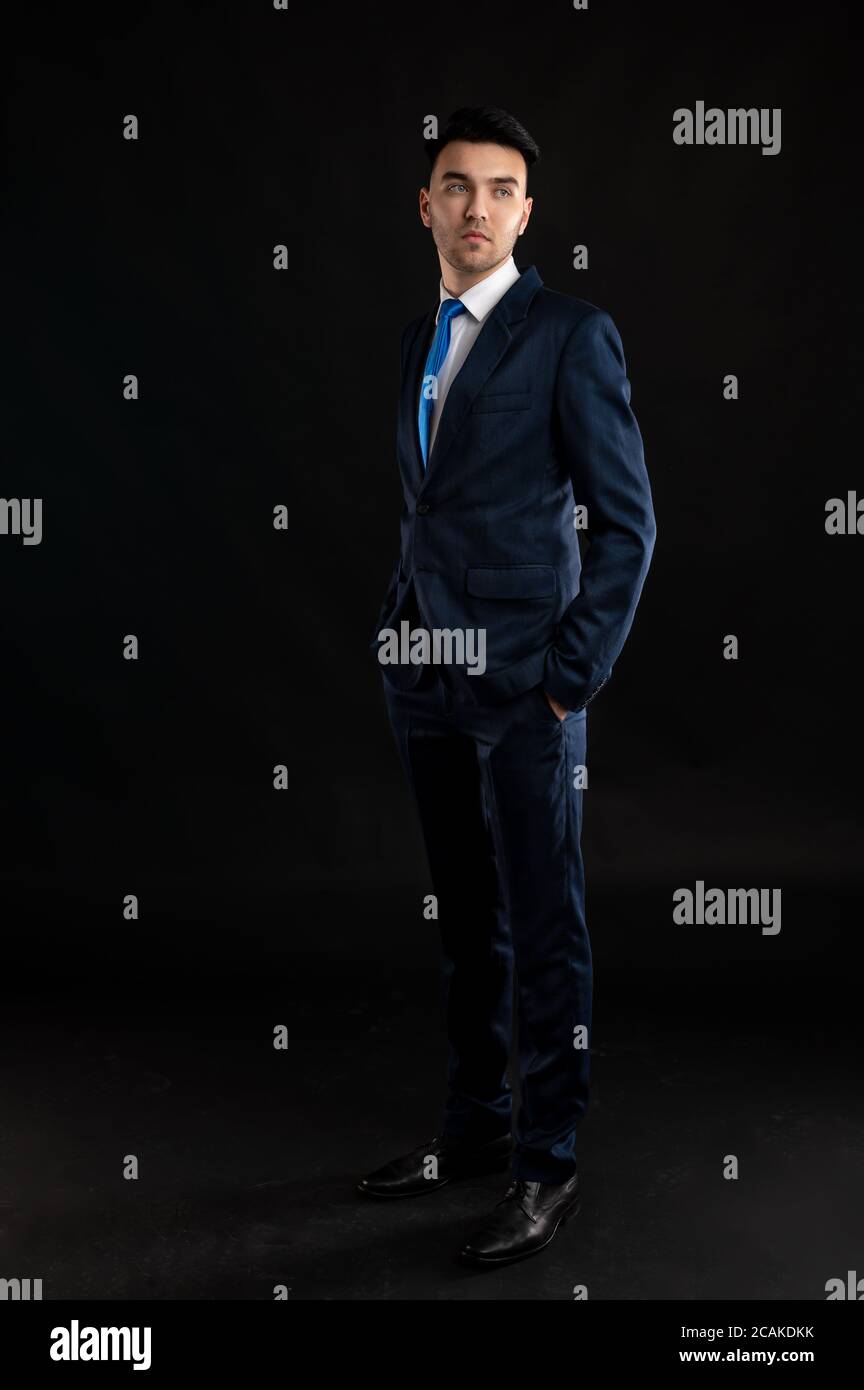 Ganzkörperportraitof Business-Mann trägt blauen Business-Anzug und Krawatte isoliert auf schwarzem Hintergrund Stockfoto