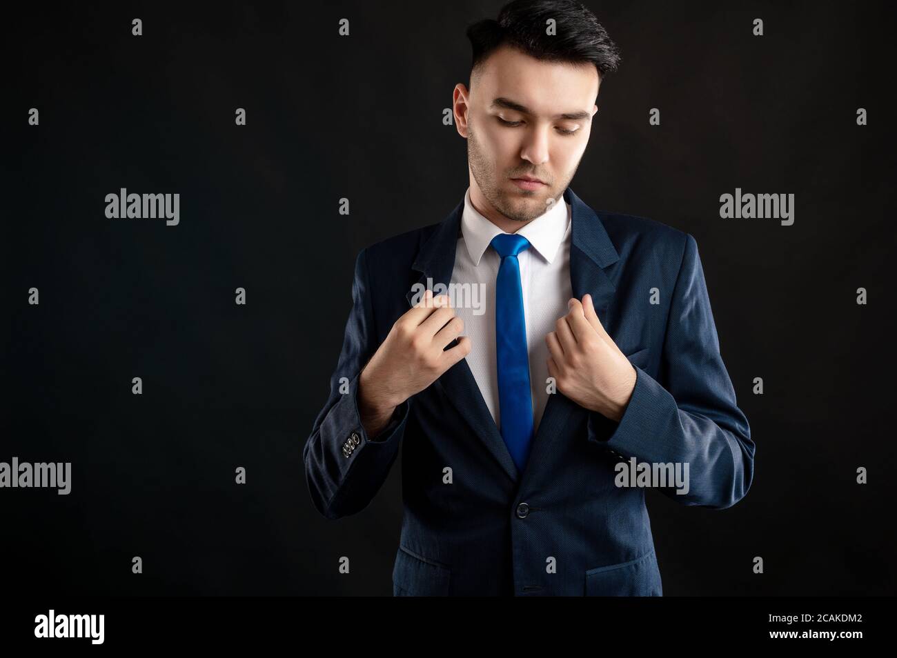 Porträt eines Geschäftsmanns, der seinen Geschäftsanzug isoliert arrangiert Schwarzer Hintergrund mit Werbungsfläche Stockfoto