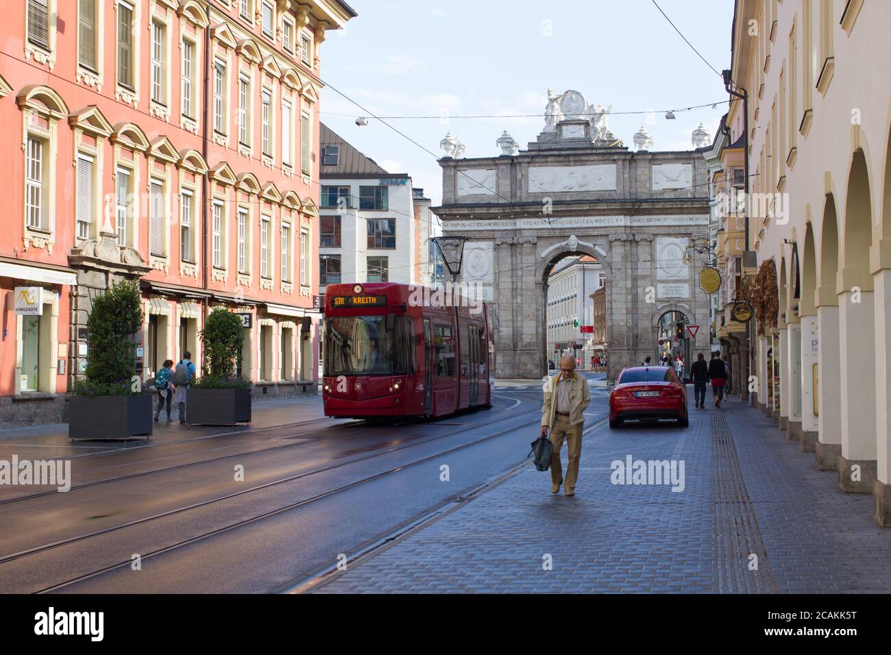 Innsbruck / Österreich - September 2019: Ein Mann läuft entlang der Straßenbahnlinien in der Nähe des Triumphbogens im Zentrum von Innsbruck nach Hause Stockfoto