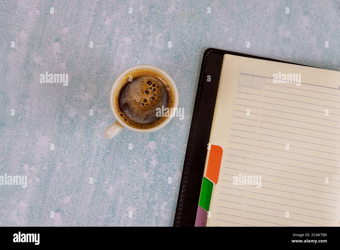 Arbeitsplatz Objekte Draufsicht Tasse Kaffee, ein wöchentliches Notizbuch mit Plänen für die Woche einer Person Stockfoto