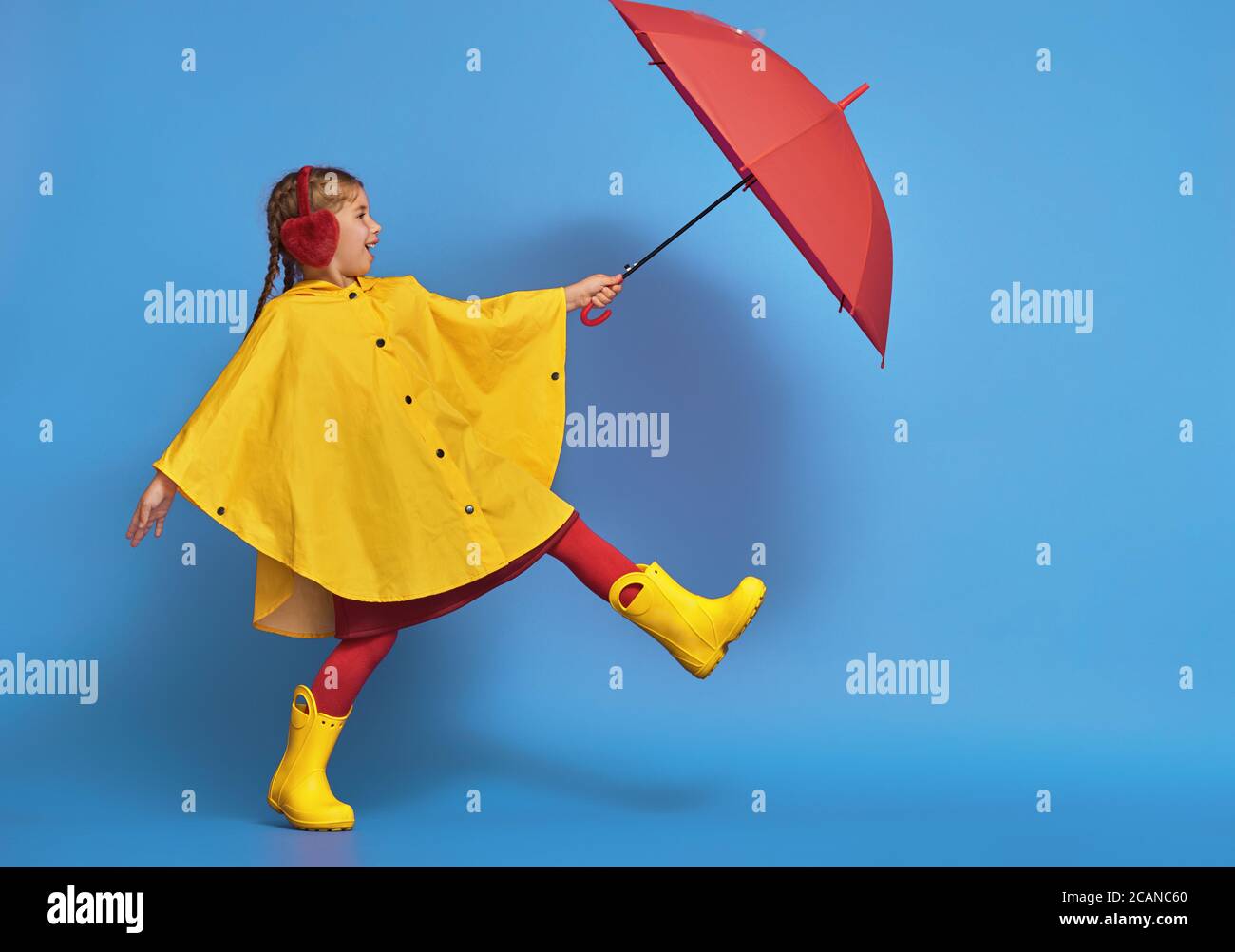 Glucklich Lustiges Kind Mit Rotem Regenschirm Posiert Auf Blauem Wandhintergrund Madchen Tragt Gelbe Regenjacke Und Gummistiefel Stockfotografie Alamy
