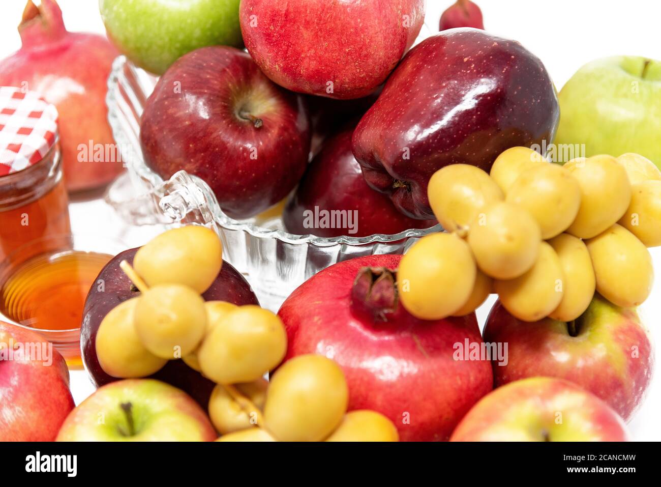 Rosh Hashanah, Jüdisches Neujahr, traditionelle Symbole, Honig im Glas, Granatäpfel, Datteln, rote und grüne Äpfel. Isoliert auf WEISSEM Hintergrund Stockfoto