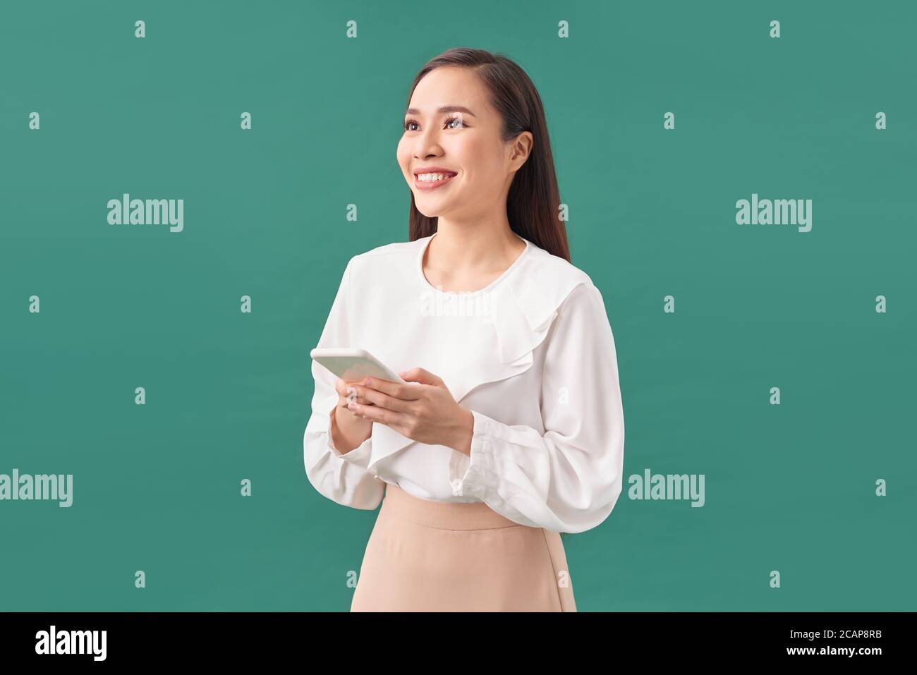 Fröhlich niedlich schöne junge Frau Chat mit Handy isoliert über türkisfarbenen Hintergrund. Blick zur Seite Stockfoto