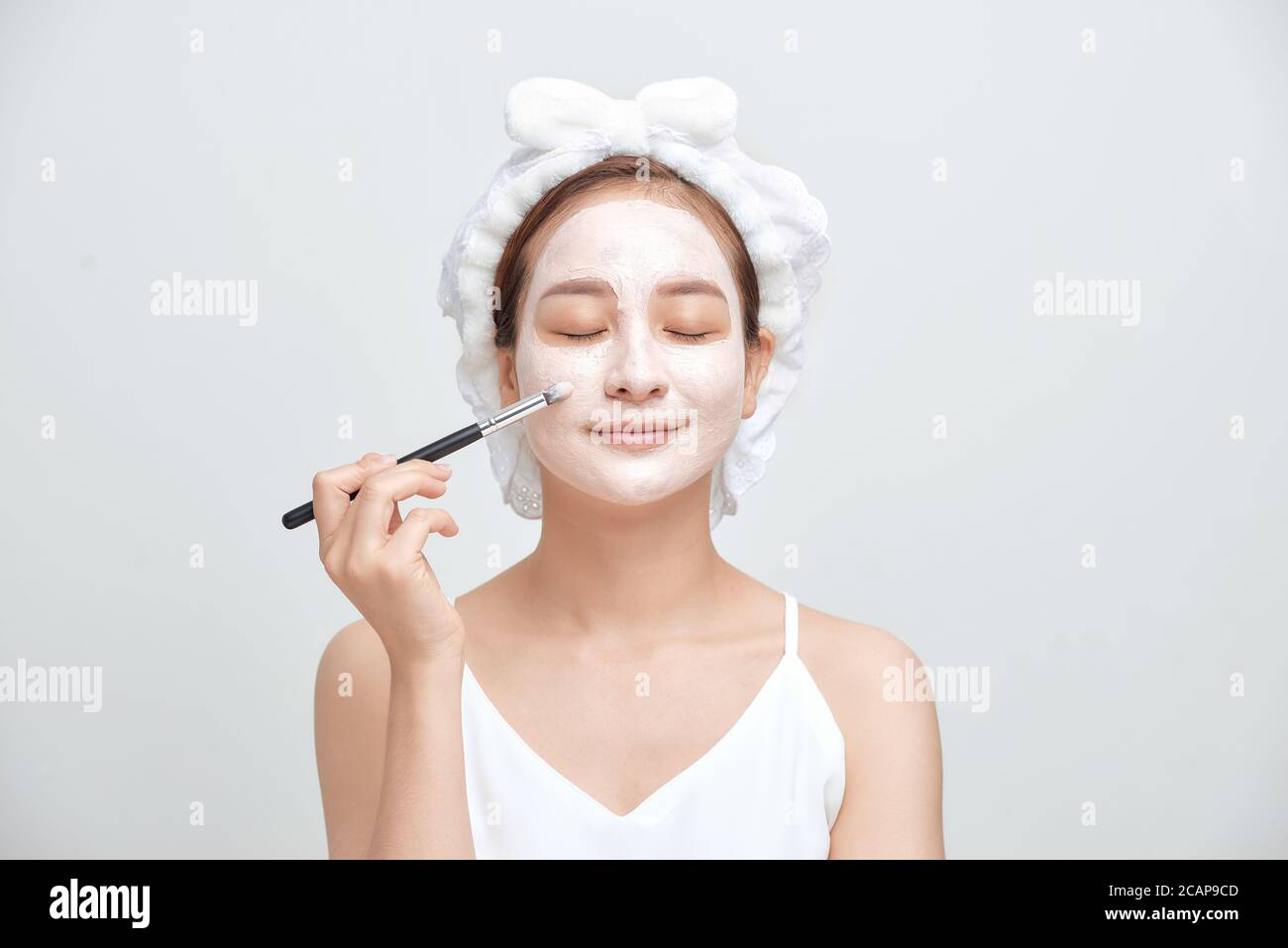 Attraktive Spa Frau Anwendung Gesichts-Ton-Maske auf weißem Hintergrund isoliert. Stockfoto
