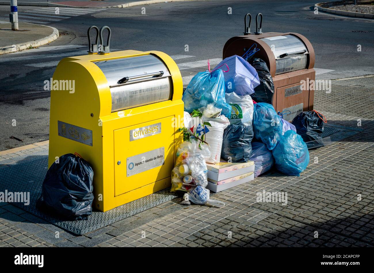 Volle Müll- und Recycling-Mülleimer mit Mülltüten auf dem Boden. Stockfoto