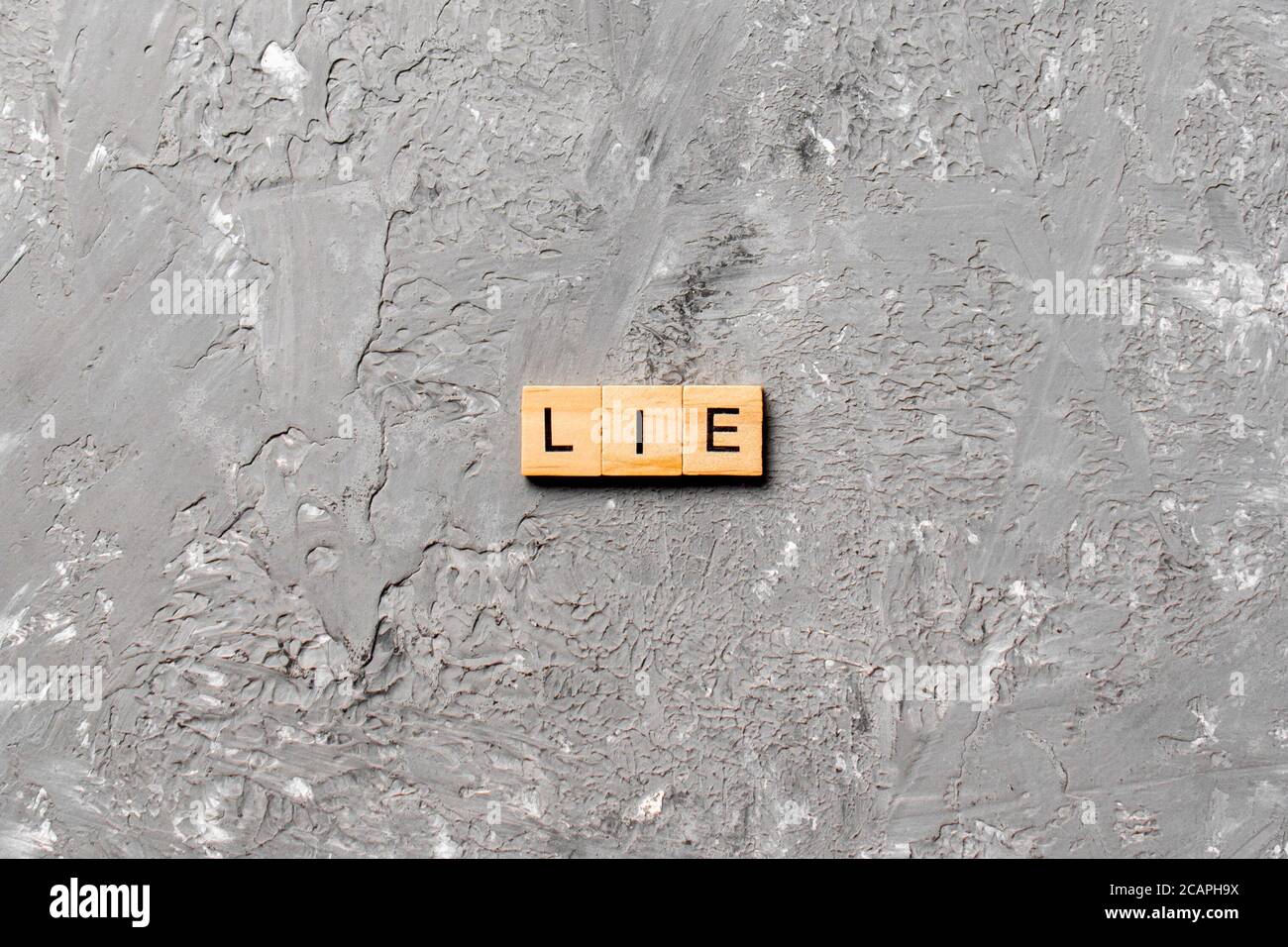 LIE Wort auf Holzblock geschrieben. LEGEN Sie Text auf Zementtisch für Ihr Design, Konzept. Stockfoto
