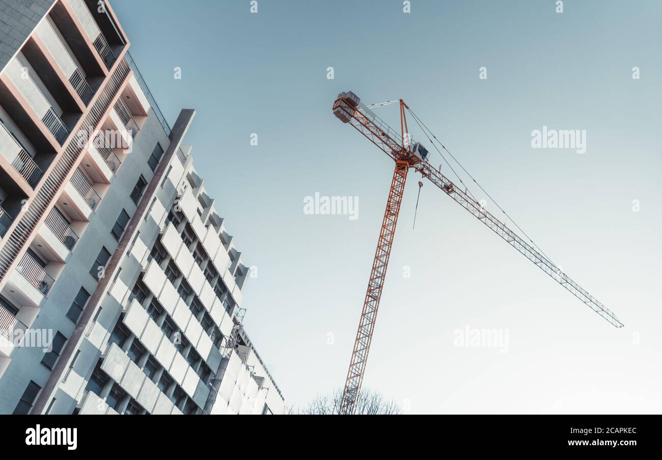 Schräge diagonale Ansicht vom Boden einer hohen Konstruktion Kran in einem Wohnviertel in der Nähe eines Wohnhauses mit Klarer blauer Himmel im Hintergrund Stockfoto