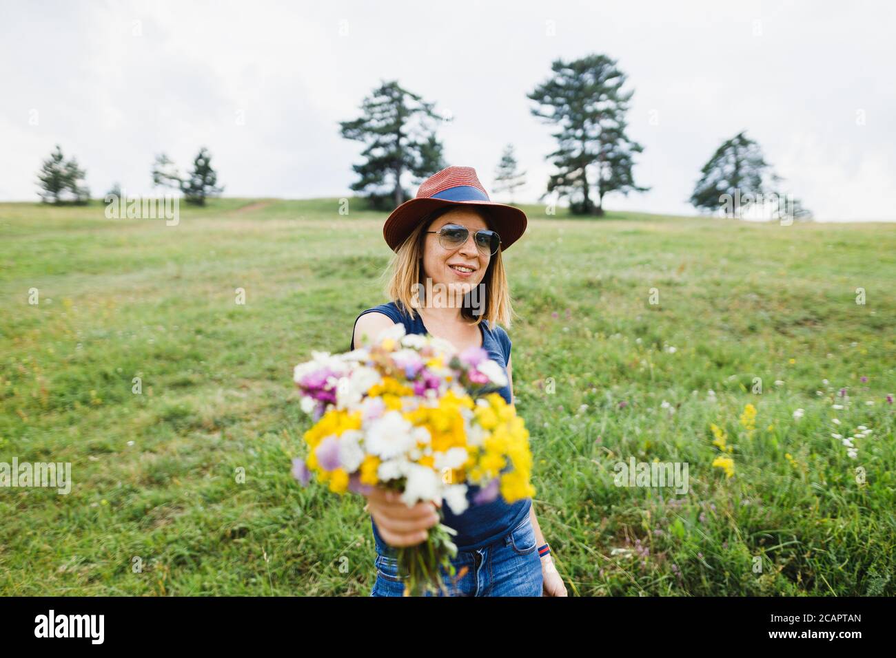 Junge Frau hält Blumenstrauß auf dem Feld Stockfoto