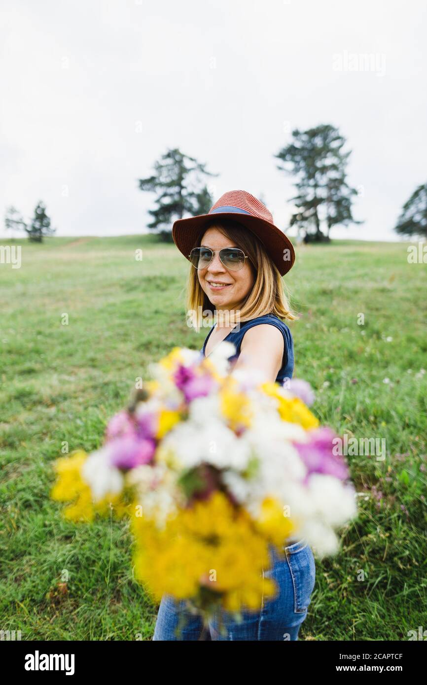 Junge Frau hält Blumenstrauß auf dem Feld Stockfoto