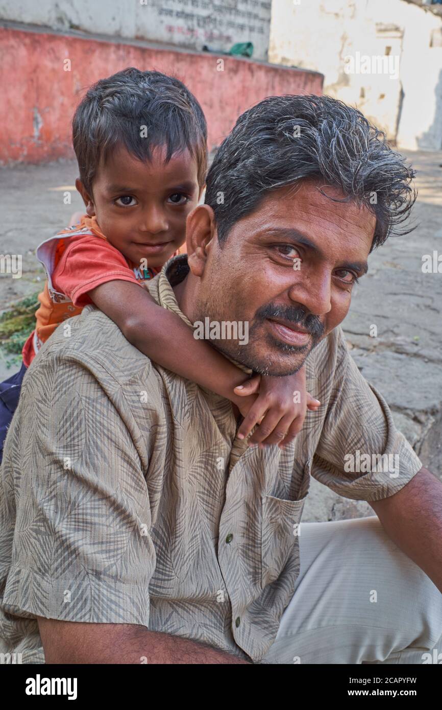 Porträt eines indischen Vaters, liebevoll von seinem jungen Sohn umarmt; in einer Straße in Mumbai, Indien Stockfoto