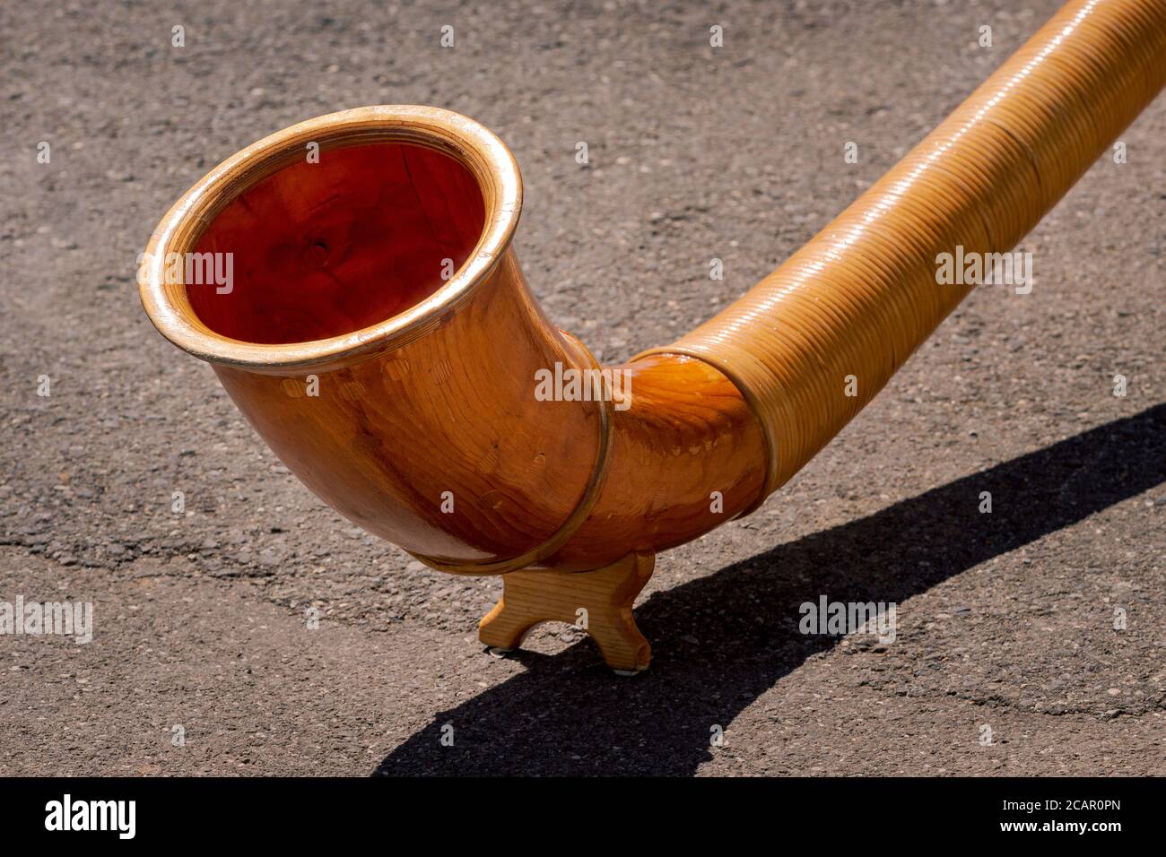 Eine Nahaufnahme des Endes des hölzernen Alphorns (Alpenhorn oder Alpenhorn) auf einem betonierten Hintergrund. Traditionelles Instrument in der Schweiz Stockfoto