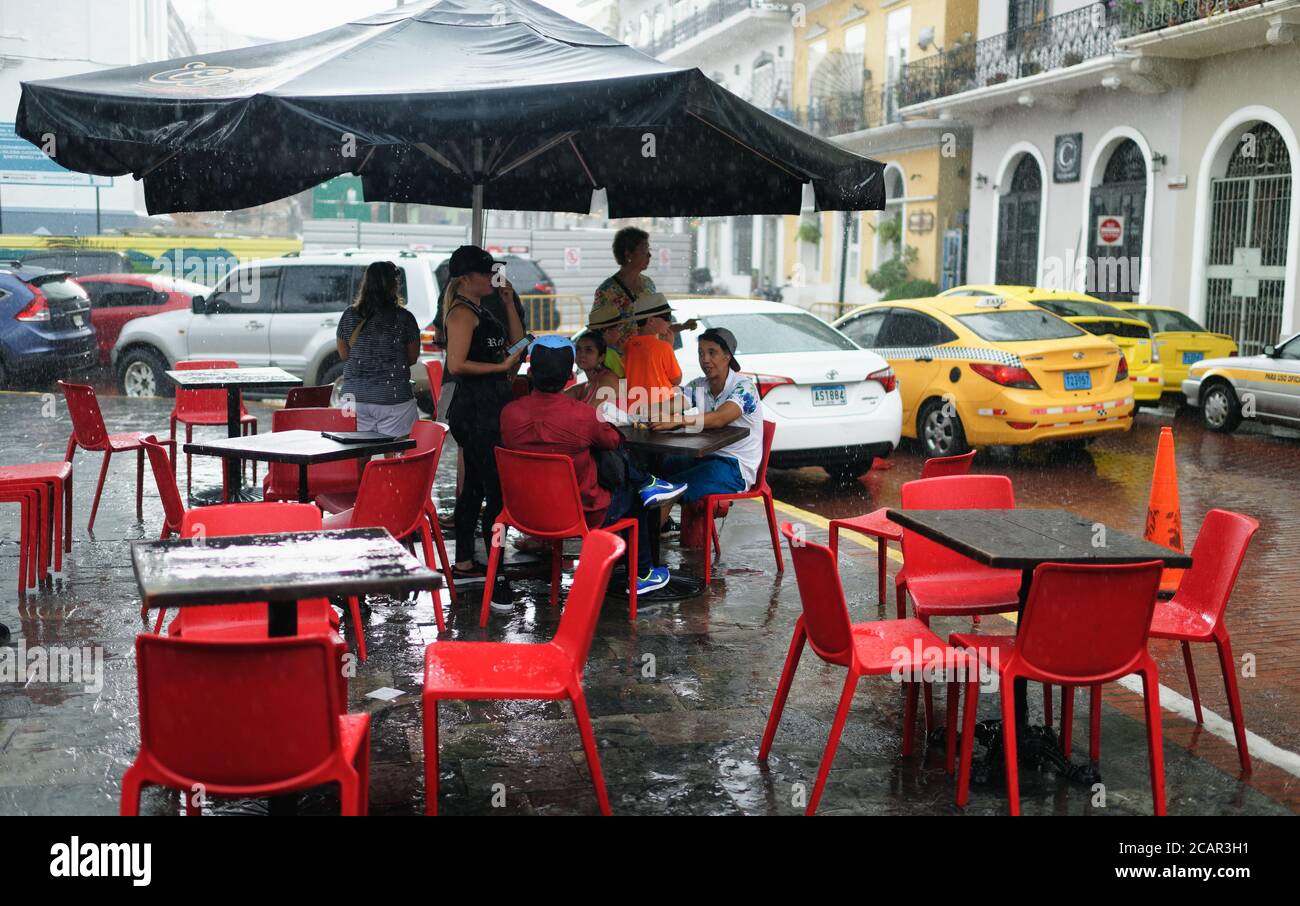 Menschen drängten sich unter dem Dach einer Bar vor einem sintflutartigen Regen in Panama City, Zentralamerika, zu schützen Stockfoto