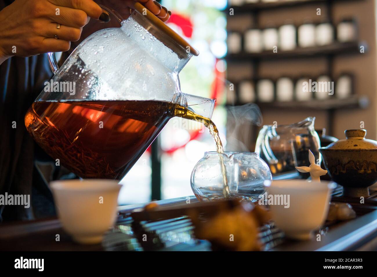 Traditionelle Chinesische Teezeremonie. Schwarzer oder roter Tee Gießen aus Glas große Teekanne in Glas Chahai auf dunklen Holztisch Hintergrund Stockfoto