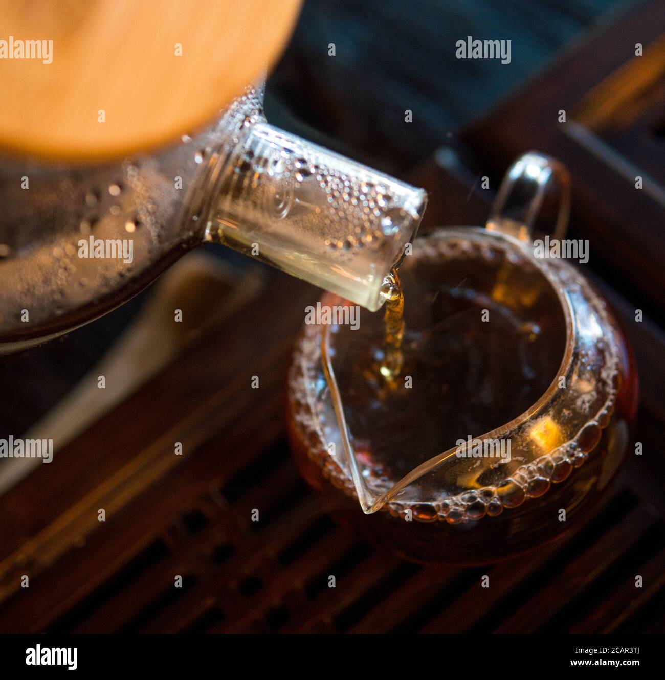 Traditionelle Chinesische Teezeremonie. Schwarzer oder roter Tee Gießen aus Glas große Teekanne in Glas Chahai auf dunklen Holztisch Hintergrund Stockfoto