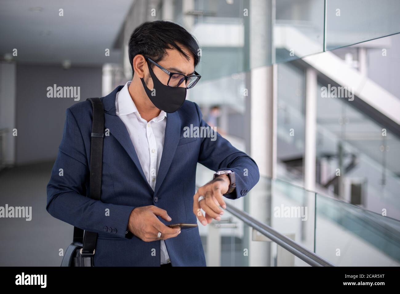 Asiatische Geschäftsmann trägt eine Maske und beobachten Zeit, bevor sie zur Arbeit in den Morgen. Stockfoto