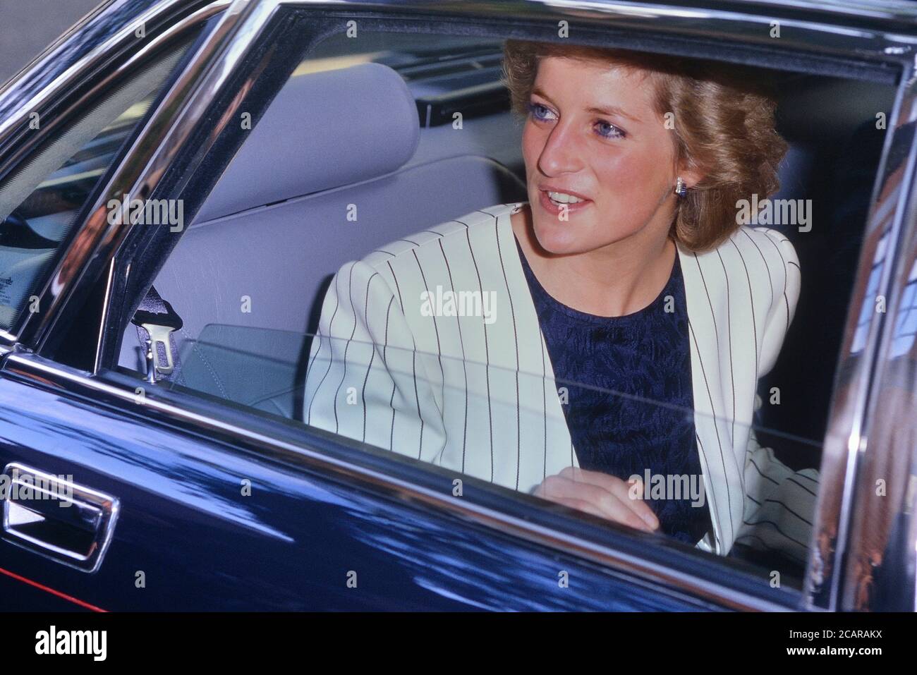 Diana, Prinzessin von Wales in schwarz-weißer Nadelstreifenjacke in einem Auto mit Chauffeur ohne Sicherheitsgurt, London, England. 1989 Stockfoto