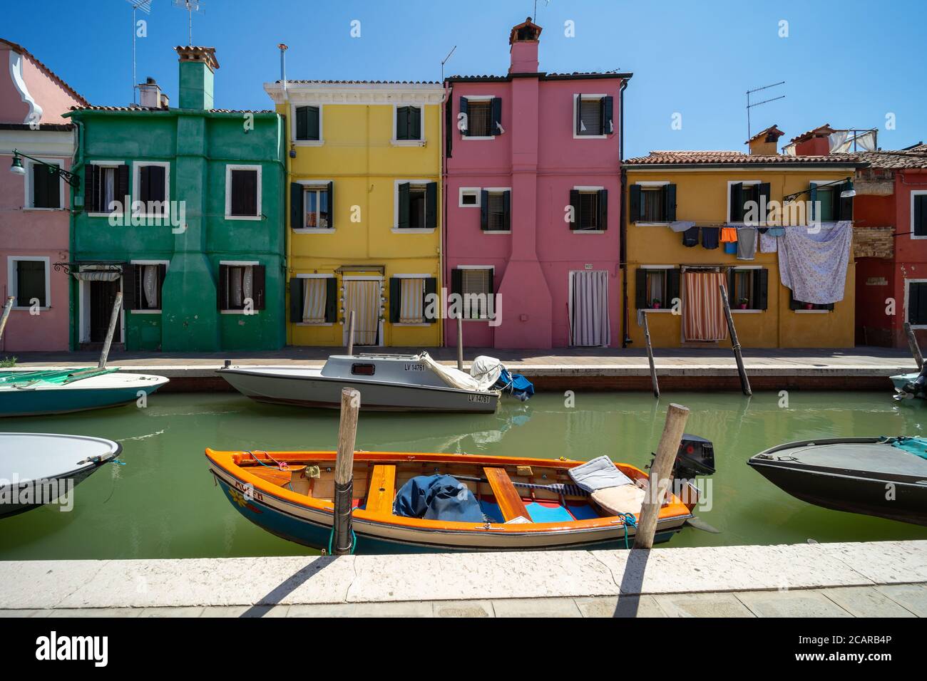 Burano Insel, Lagune von Venedig, Venedig, Italien, Panorama mit den typischen farbigen Häusern Fronten auf einem Kanal und einem kleinen Boot in der Innenstadt Stockfoto