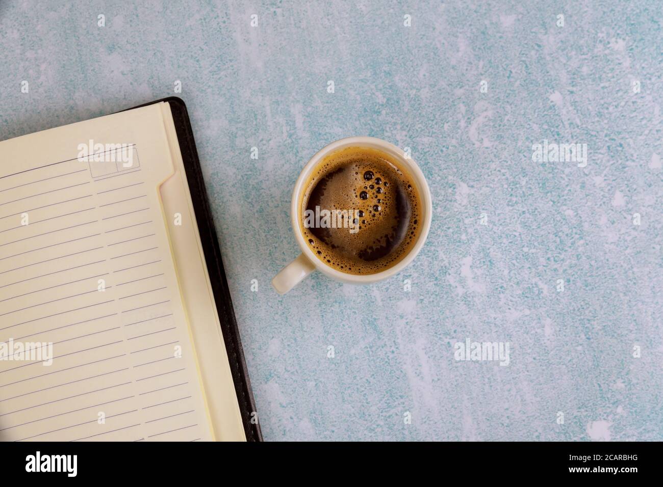 Kaffeetasse und wöchentliches Notizbuch mit Planungsarbeitsplatzobjekten top Anzeigen Stockfoto