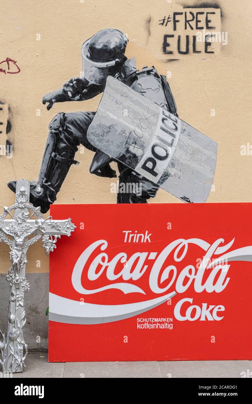 Hamburg, Deutschland, 23. März 2019 - beunruhigendes Mauergraffiti in der Stadt: Ein Polizist tritt auf ein Kruzifix, mit einer Coca-Cola-Anzeige daneben. Stockfoto