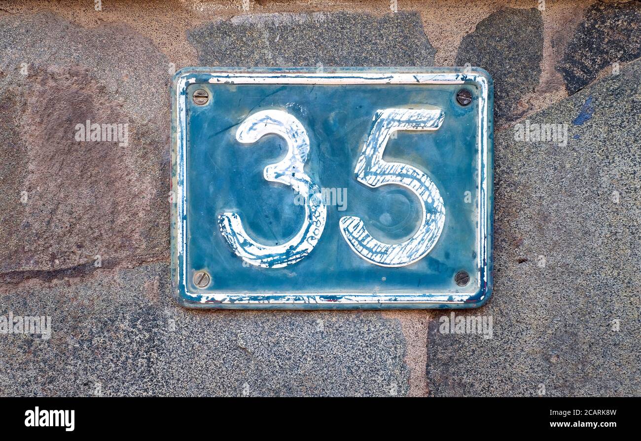 Fünfunddreißig, Zahl 35, blaues Ziffernschild auf steingrauem Hintergrund. Stockfoto