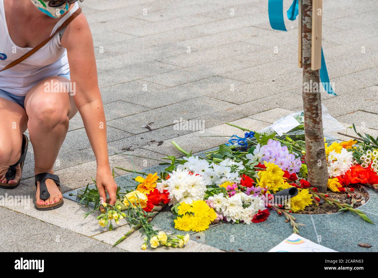 Ein Weibchen legt eine Blume zu Ehren des durch COVID-19 getöteten Gesundheitspersonals in Basildon, Essex, Großbritannien. Blumen erinnern an 540 tote Angestellte an der Rezeption. Blumen Stockfoto