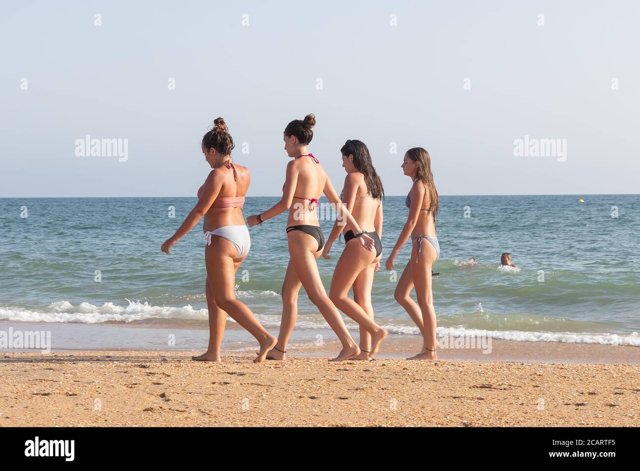 Punta Umbria, Huelva, Spanien - 7. August 2020: Eine Gruppe von Frauen, die am Strand spazieren, tragen keine schützenden oder medizinischen Gesichtsmasken. Stockfoto