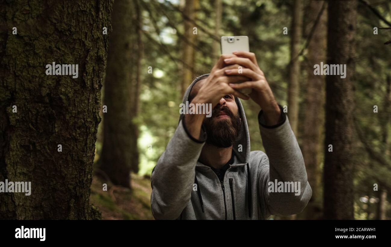 Teenager SMS im Wald mit einem Telefon in der Hand bricht das Signal, betonte junger Mann mit Signalproblemen Stockfoto