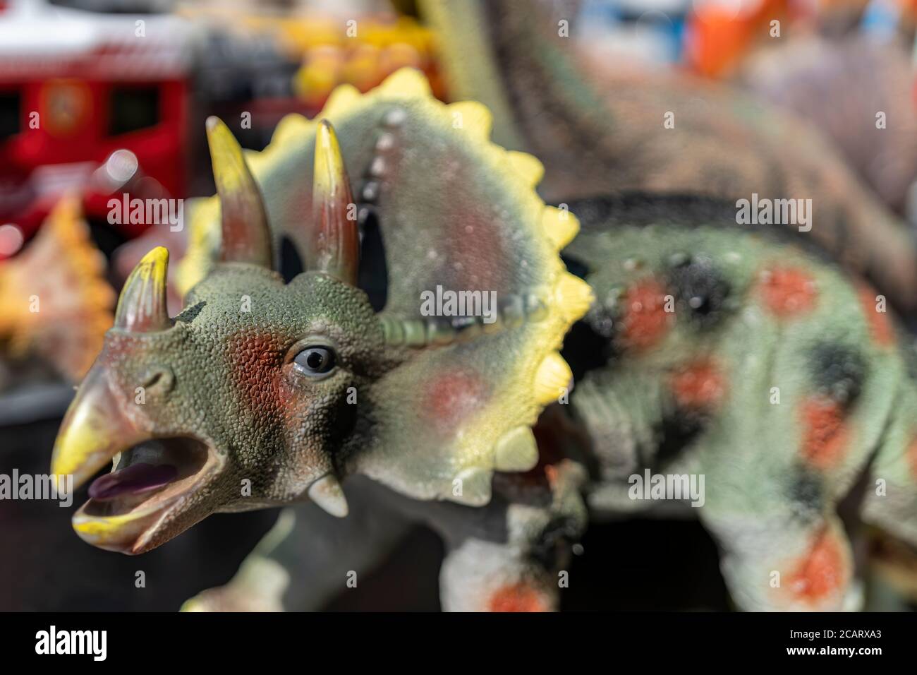 Plastikdinosaurier (Triceratops) auf einem Flohmarkt in Hamburg. Makrofotografie des Kopfes mit einem verwacklungsunscharfen Verlauf. Stockfoto