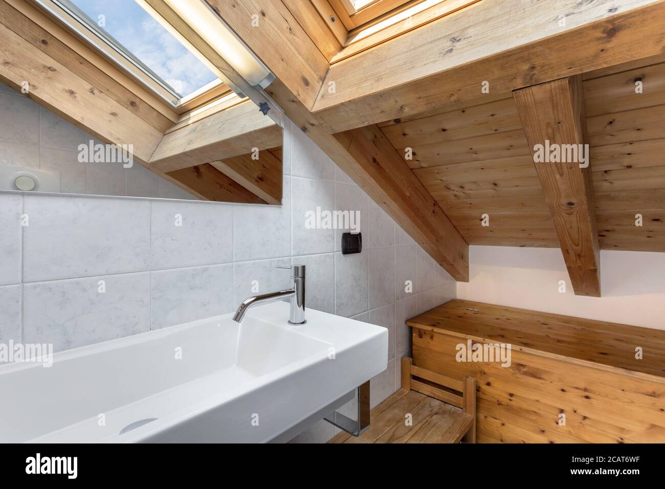 Praktisches und gemütliches Badezimmer mit Holzmöbeln. Dach mit freiliegenden Holzbalken und Himmelfenster. Italienischer Stil. Stockfoto