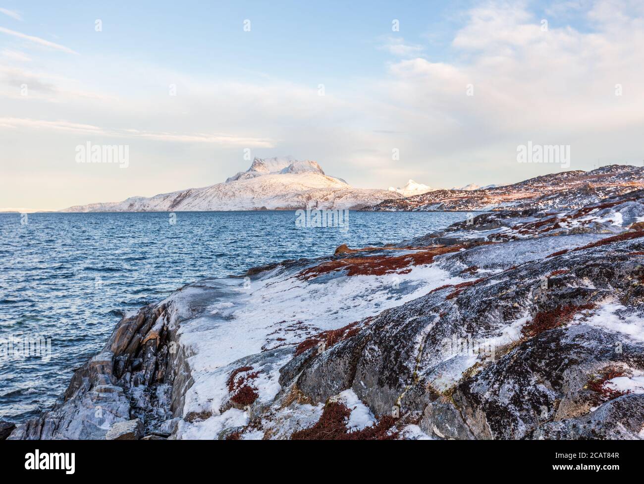 Tiefgefrorene Tundralandschaft mit kaltem grönländischen Meer und schneebeeten Sermitsiaq-Bergen im Hintergrund, nahe der Stadt Nuuk, Grönland Stockfoto