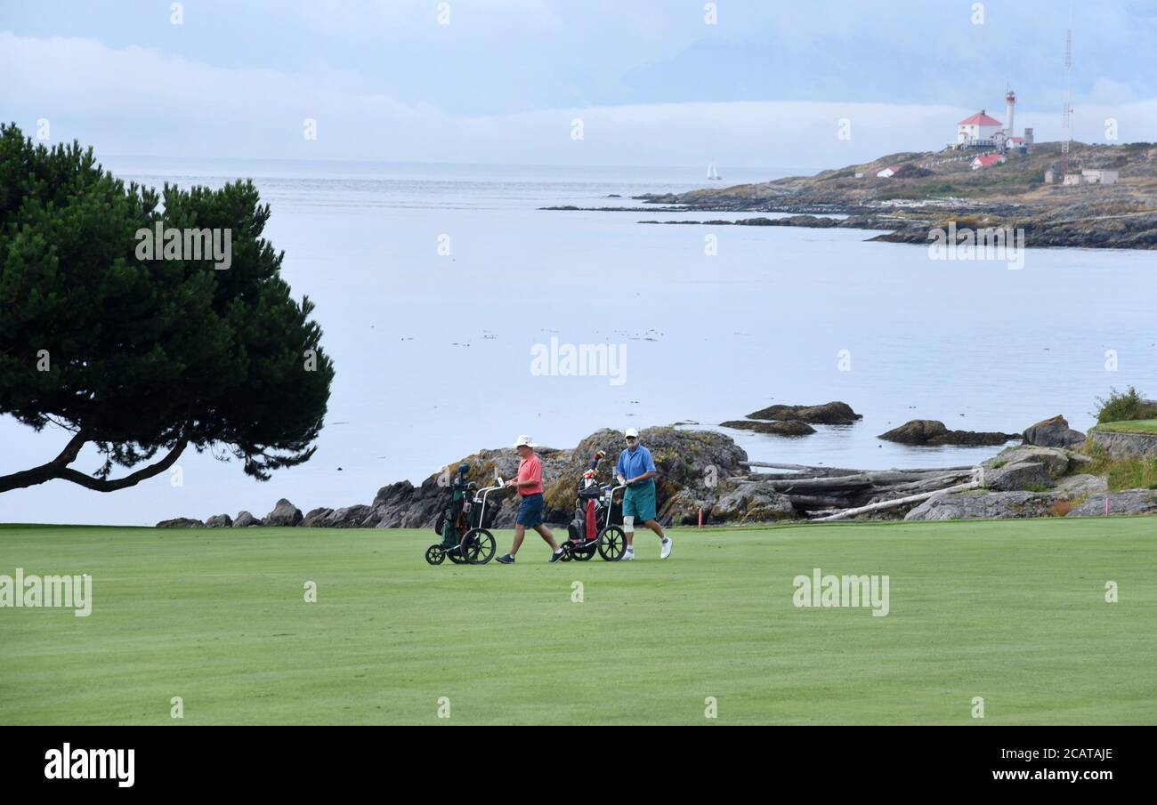 Golfer genießen den Golfplatz und den Blick auf das Meer im Victoria Golf Club in Oak Bay, British Columbia, Kanada auf Vancouver Island. Im Hintergrund befindet sich die Stockfoto