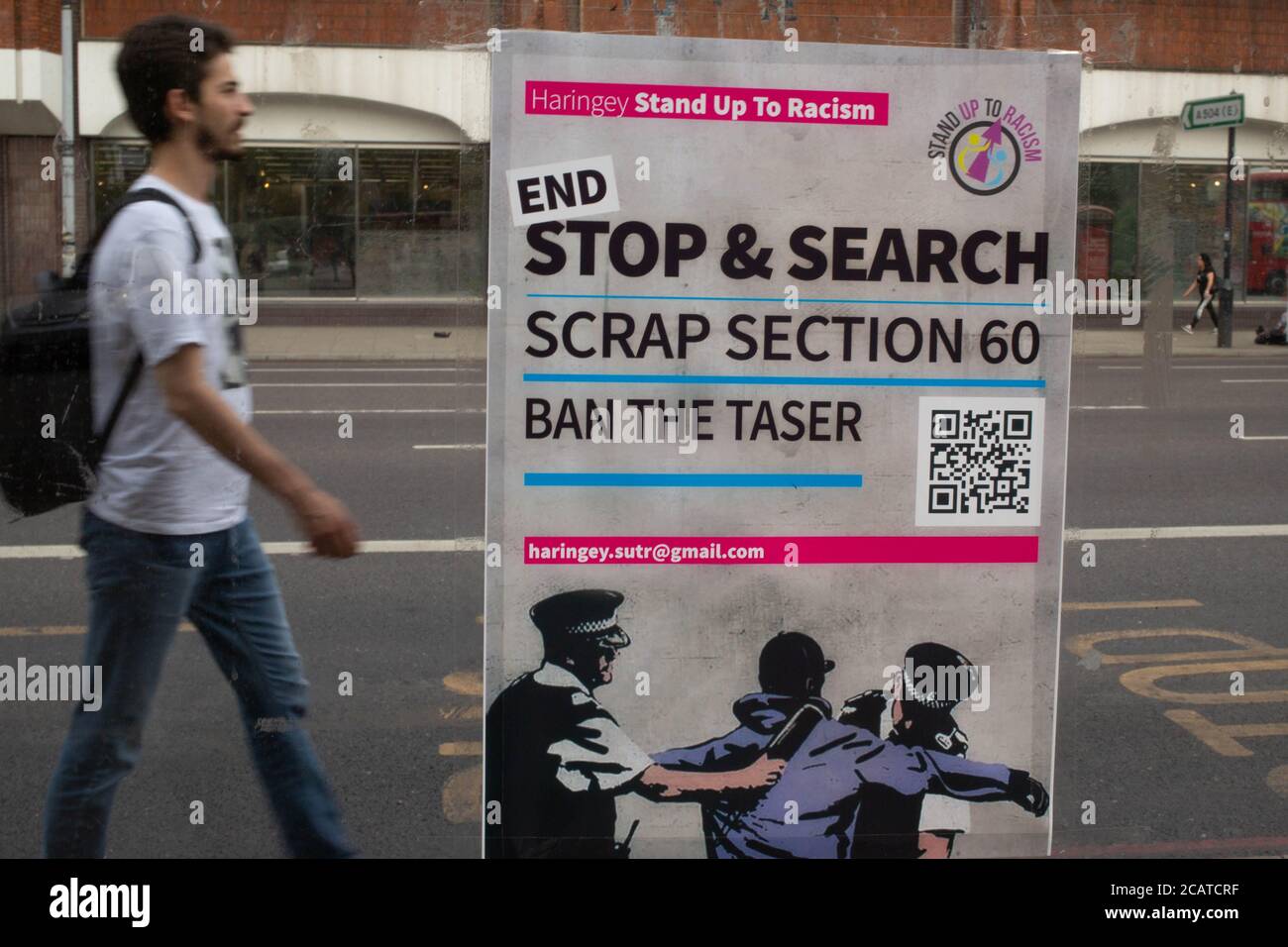 Ein Mann kommt an einem Plakat vorbei, auf dem ein Ende der Sektion 60 in der Nähe der Tottenham Polizeistation gefordert wird. Demonstranten fordern die Regierung auf, Sektion 60 (argwöhnloses Stopp und Durchsuchen) abzuschaffen. Stockfoto