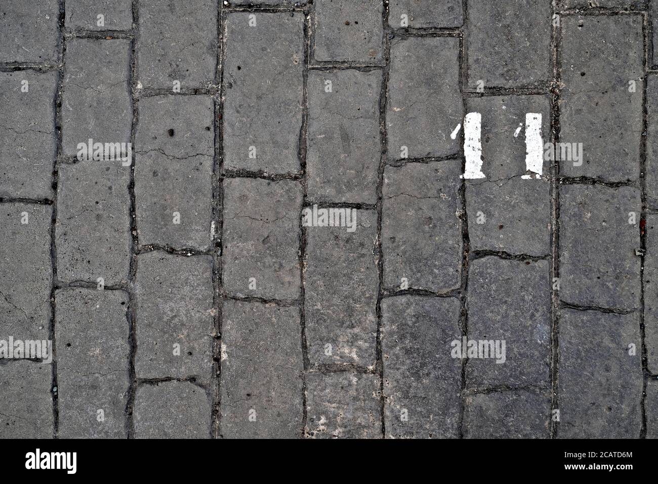 11, Nummer elf, weiße Schablonenzahl auf Kopfsteinpflaster. Stockfoto