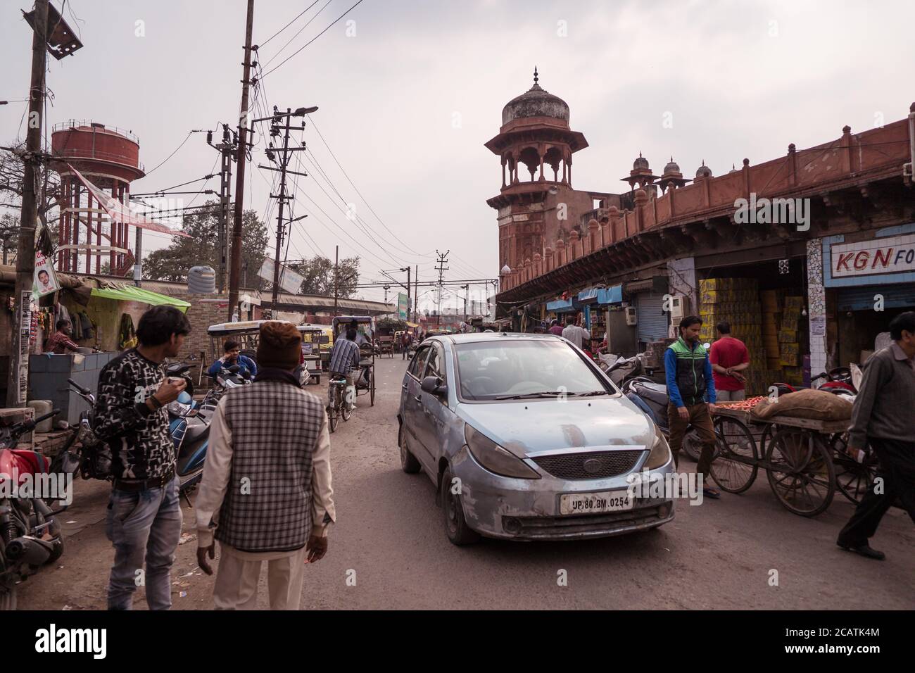 Agra / Indien - Februar 12, 2020: Menschen und Fahrzeuge auf belebten Straße vor rötlichen Mauern des berühmten Jama Masjid Stockfoto