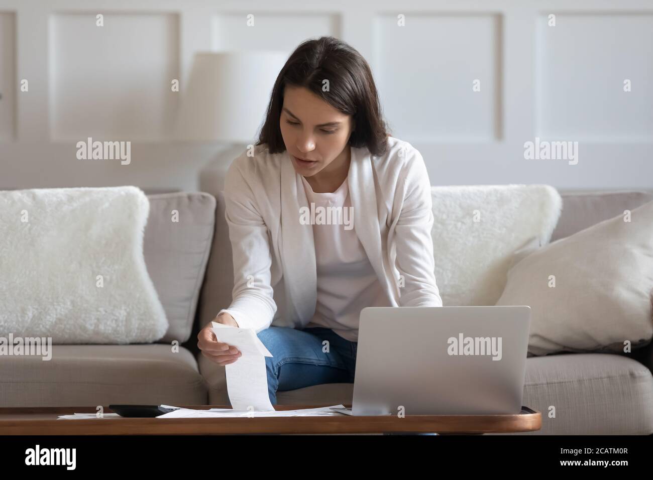 Fokussierte junge Dame, die das monatliche Haushaltsbudget verwaltet. Stockfoto