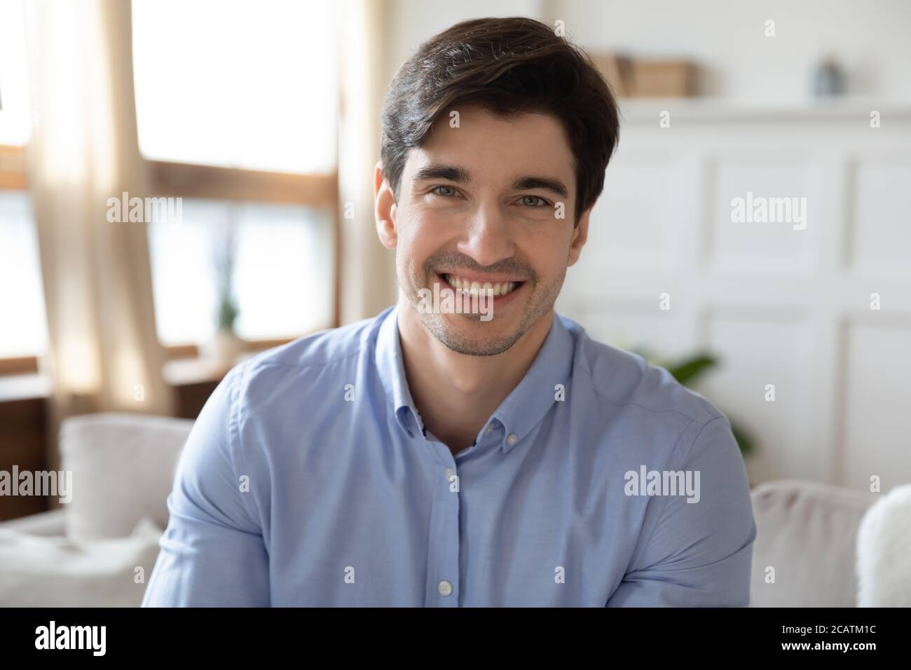 Profilbild eines jungen, gutaussehenden Mannes, der auf dem Sofa sitzt. Stockfoto