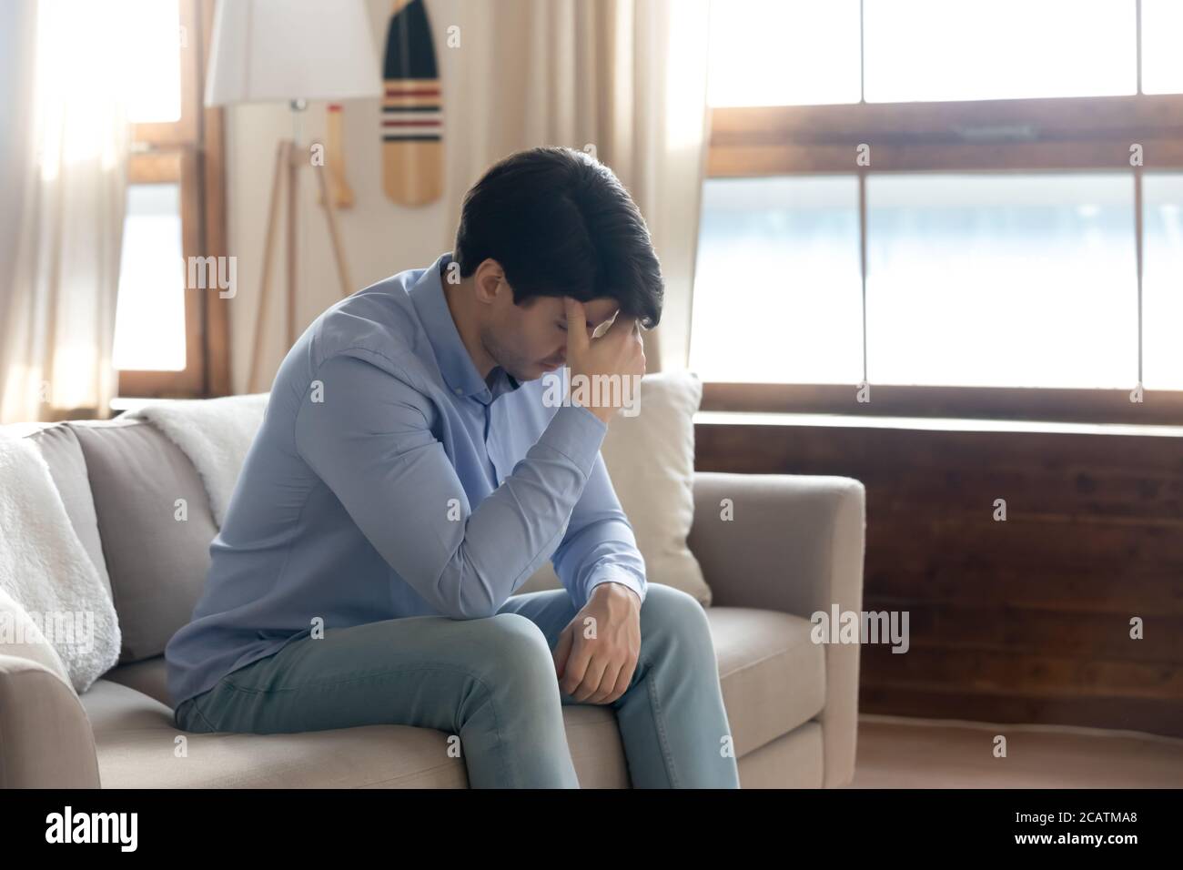 Gestresster junger Mann denkt an Lebensprobleme im Haus. Stockfoto