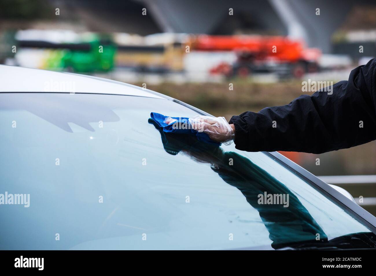 Die Windschutzscheibe eines Autos mit einem Mikrofasertuch von Hand reinigen. Frontscheibenscheibe für Waschfahrzeuge. Stockfoto